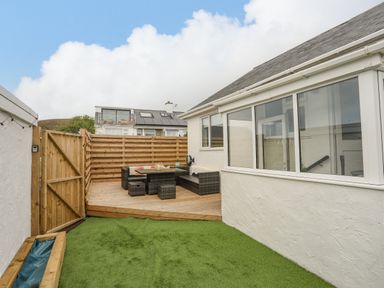 An outdoor area with artificial grass and a wooden deck with garden furniture at Watlands in Mynytho near Abersoch