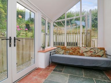 A room with glass doors a sofa and tiled floor at Rose Cottage in Okehampton