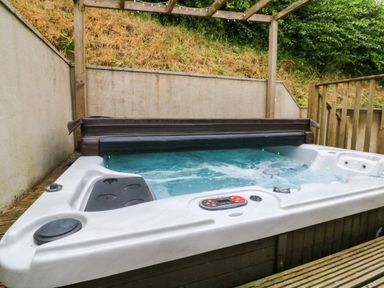 An outdoor hot tub with water jets and a control panel on a wooden deck area at Rose Cottage in Okehampton