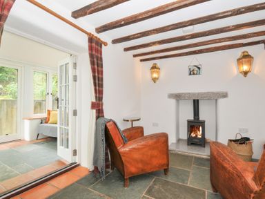 A living room with an armchair and a wood stove at Rose Cottage Okehampton