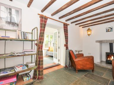 A living room with a chair and a bookshelf at Rose Cottage Okehampton