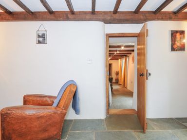 A snug area with a chair and a door leading to another room at Rose Cottage Okehampton