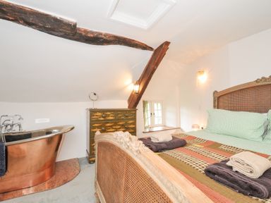 A bedroom with a bathtub and bed at Rose Cottage in Okehampton