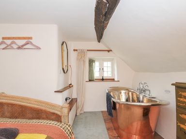 A bathroom with a copper bathtub and window at Rose Cottage Okehampton