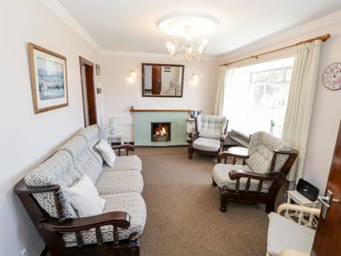 A living room with a sofa and armchairs around a fireplace at Sea Watch House in Roundstone County Galway