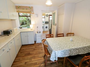A kitchen with a dining table covered with a patterned tablecloth and wooden chairs at Sea Watch House in Roundstone County Galway