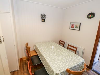 A dining room with a rectangular table covered with a patterned tablecloth surrounded by wooden chairs at Sea Watch House in Roundstone County Galway