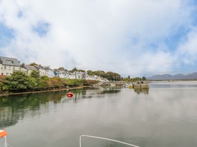 A river with houses along the shore and boats on the water at Sea Watch House in Roundstone County Galway
