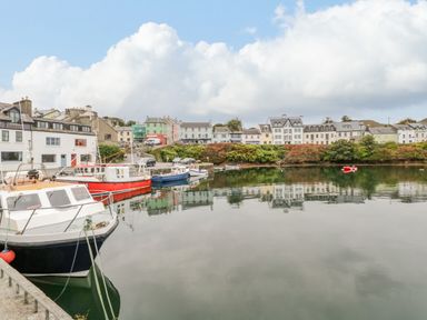 A harbor with boats docked along the water and buildings in the background at Sea Watch House in Roundstone County Galway
