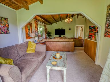 A living room with couches a wooden coffee table a television and a chandelier at Lakeside Lodge Retreat in Tattershall