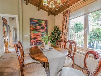 A dining room with a wooden table and chairs next to a large window at Lakeside Lodge Retreat in Tattershall