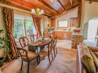 A dining area with table and chairs next to a kitchen with wooden cabinets and tiled floor at Lakeside Lodge Retreat in Tattershall