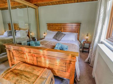 A bedroom with a wooden bed with pillows and towels two lamps on bedside tables and a wooden chest at Lakeside Lodge Retreat in Tattershall