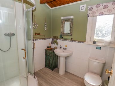 A bathroom with a shower, pedestal sink, toilet, small cabinet, and window at Lakeside Lodge Retreat in Tattershall