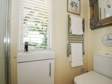 A bathroom with a sink under a window with blinds and a towel rack with towels at Orchard Retreat East Worlington near Witheridge