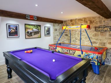 A game room with a purple pool table and an air hockey table at Orchard Retreat in East Worlington near Witheridge