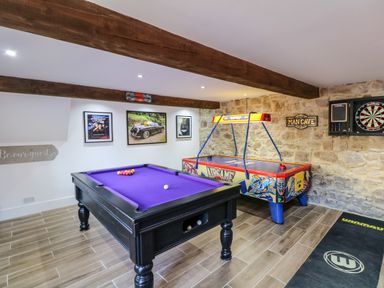 A game room with a pool table an air hockey table a dartboard and wall art at Orchard Retreat in East Worlington near Witheridge