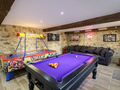A games room with a purple billiard table air hockey game dartboard and sofa at Orchard Retreat in East Worlington near Witheridge