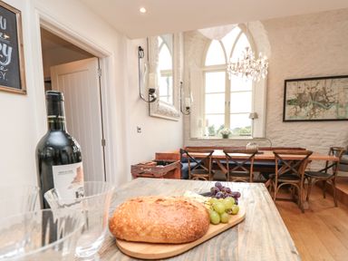 A dining room with a wooden table bread grapes wine bottle and glasses on the table at The Old Chapel in Dittisham
