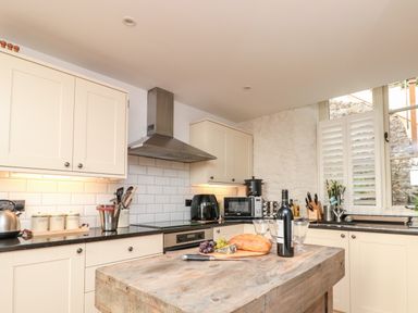 A kitchen with cream cabinets wooden island and food items on the counter at The Old Chapel in Dittisham