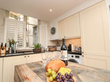 A kitchen with a wooden counter displaying bread grapes cheese wine and glasses at The Old Chapel in Dittisham