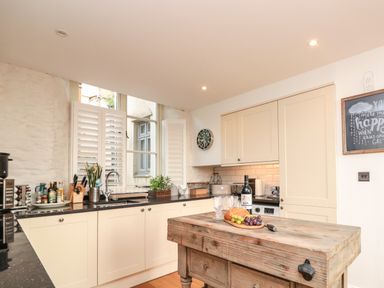 A kitchen with cream cabinets a wooden island countertop with bread grapes and wine at The Old Chapel in Dittisham
