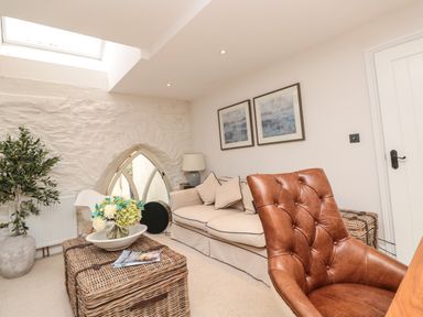 A living room with a beige sofa brown leather chair wicker coffee table and potted plant at The Old Chapel in Dittisham