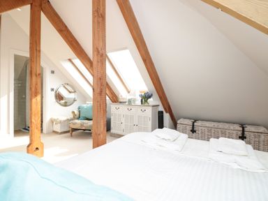 A bedroom with a bed towels dresser chair and skylight windows at The Old Chapel in Dittisham