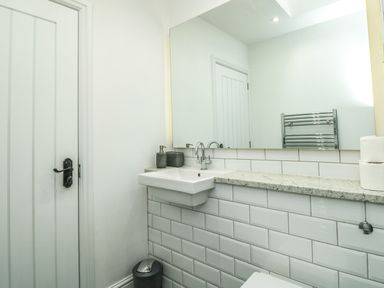 A bathroom with a sink soap dispensers large mirror and a door at The Old Chapel in Dittisham