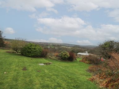 A garden with grass and bushes overlooking fields and hills at Ceunant near Newport