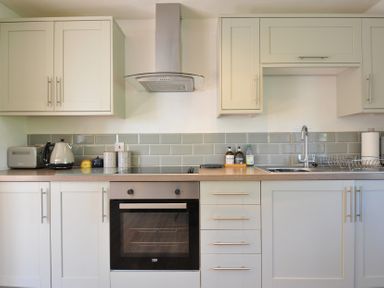 A kitchen with cabinets, oven, sink, and appliances at The Mews in Blisland