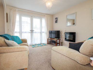 A living room with sofas a television and a wall-mounted fireplace at Smugglers in Liskeard near St Cleer