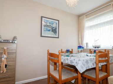A dining room with a wooden table and chairs next to a window at Smugglers in Liskeard near St Cleer