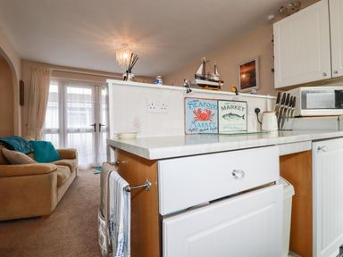 A kitchen counter with knives and seafood market signs next to a beige sofa in a living area at Smugglers in Liskeard near St Cleer