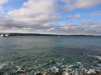 A view of a body of water with boats and a distant shoreline under a partly cloudy sky at The Annex in Wimborne Minster