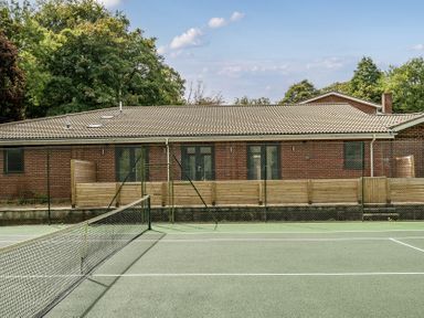 A tennis court with a building in the background at The Annex in Wimborne Minster