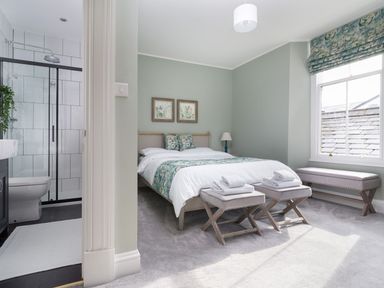 A bedroom with a double bed and folded towels on benches next to an en suite bathroom at Wansfell at Lipwood House in Windermere
