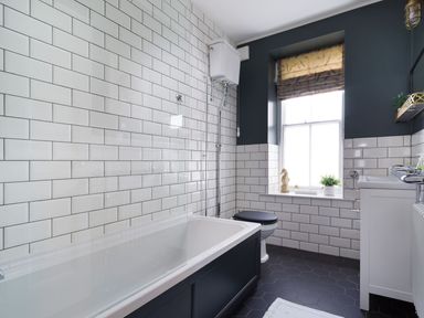 A bathroom with a bathtub, toilet, sink, and window at Wansfell at Lipwood House in Windermere
