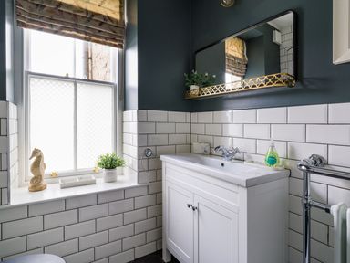 A bathroom sink with a mirror above and a window with a curtain next to it at Wansfell at Lipwood House in Windermere
