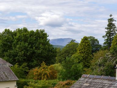A view of trees and rooftops with a mountain in the background at Wansfell at Lipwood House in Windermere