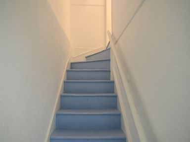 A narrow staircase with blue steps and white walls at Naunton Cottage Lyme Regis