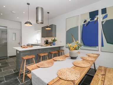 A kitchen with a wooden dining table and bar stools at Rose Cottage in Ambleside