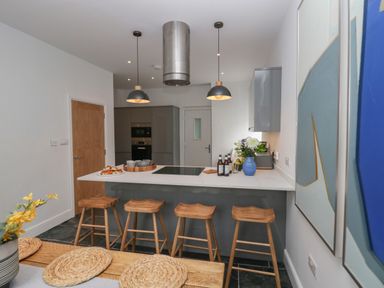 A kitchen with a breakfast bar and wooden stools at Rose Cottage in Ambleside