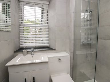 A bathroom with a sink cabinet toilet shower and window blinds at Rose Cottage in Ambleside