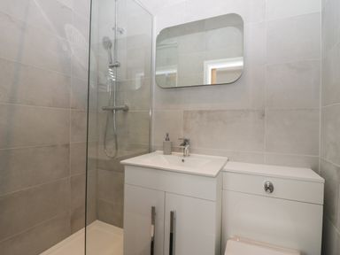 A bathroom with a shower, sink, mirror, and toilet at Rose Cottage in Ambleside