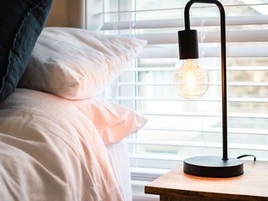 A bed with white pillows and a black lamp on a wooden bedside table at The Lookout in Polzeath