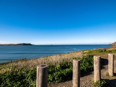 A coastal view with wooden posts and greenery overlooking the ocean at The Lookout in Polzeath