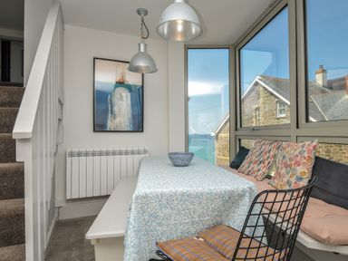 A dining room with a table and cushions at The Lookout in Polzeath