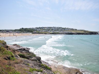 A beach with people and waves at The Lookout in Polzeath