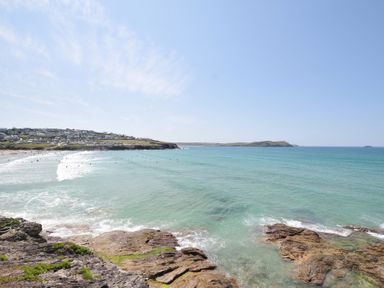 A beach with waves and surfers at The Lookout in Polzeath